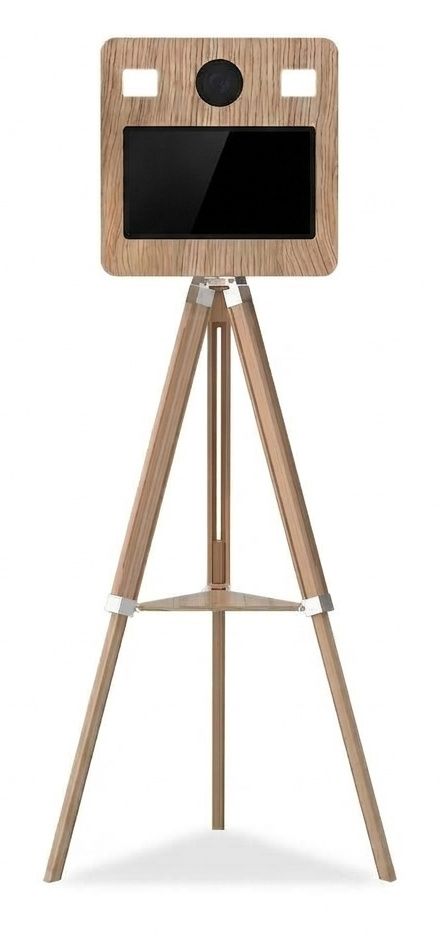 Our photo booth: a light wood unit with a camera lens, two lights and a large screen, on a wooden tripod